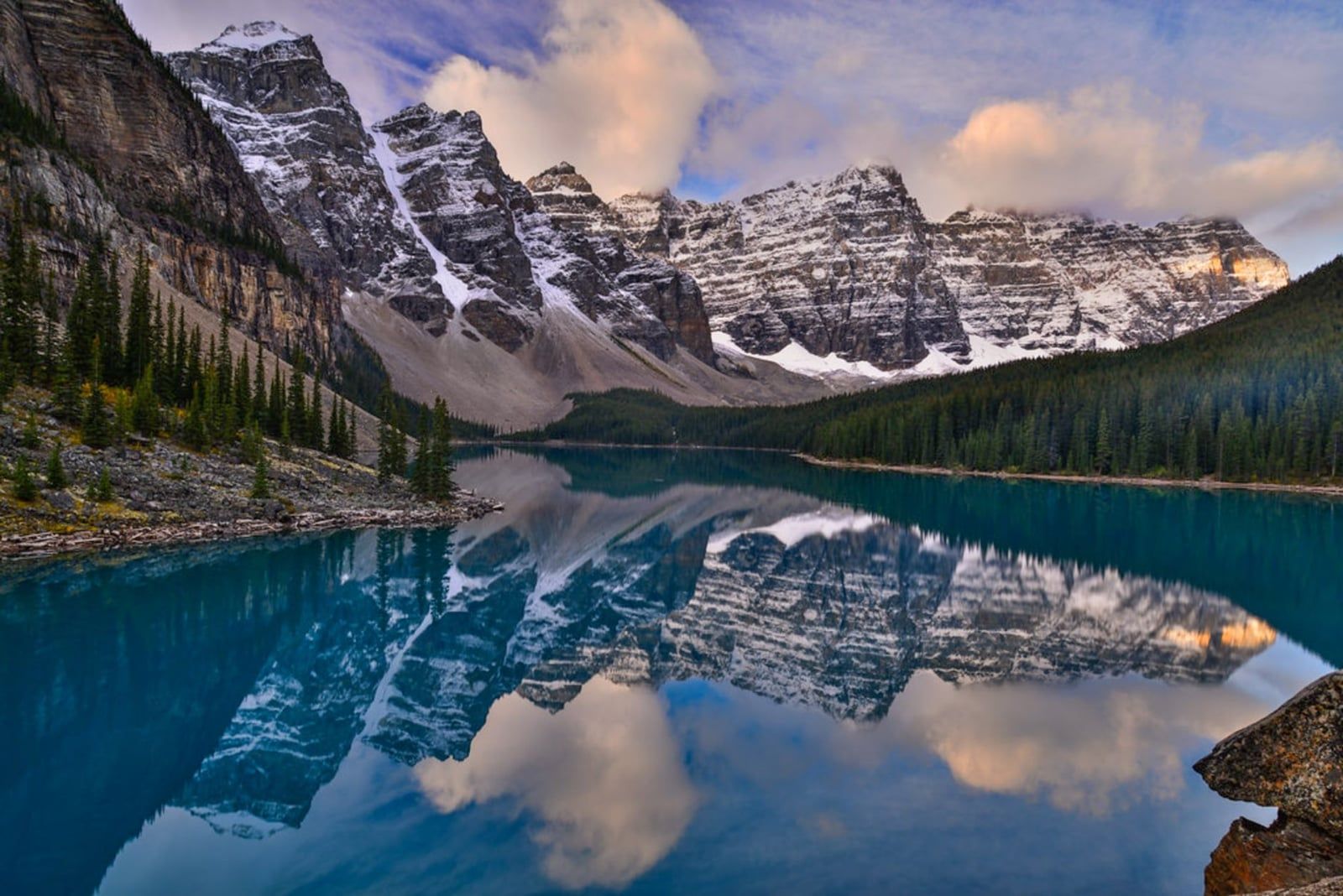 Snow-dusted mountains of the Valley of the Ten Peaks reflect in the calm blue water of Moraine Lake in Banff National Park.