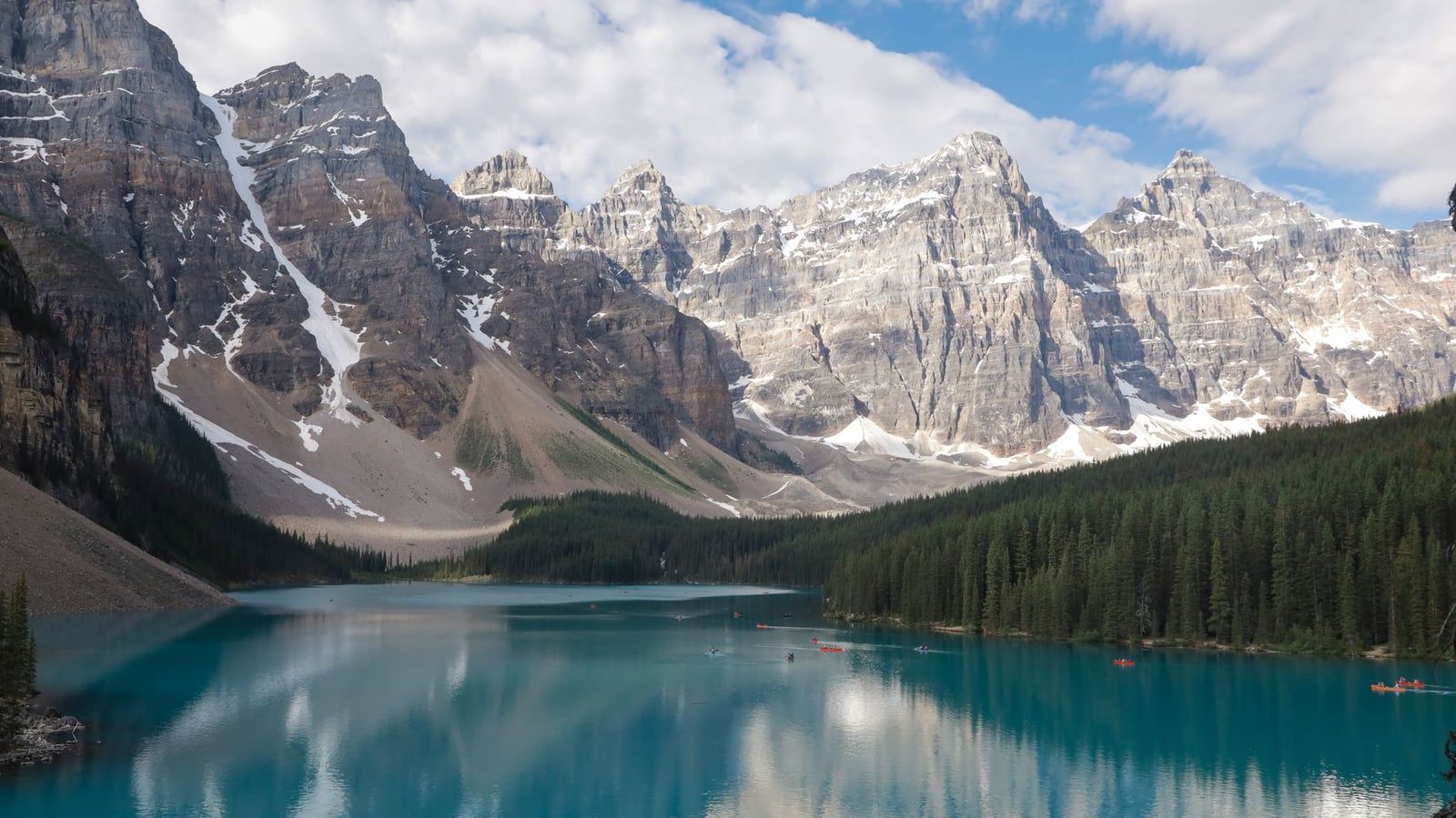 Les eaux turquoise du lac Moraine reflètent la vallée imposante des Dix Pics sous un ciel partiellement nuageux dans le parc national de Banff.