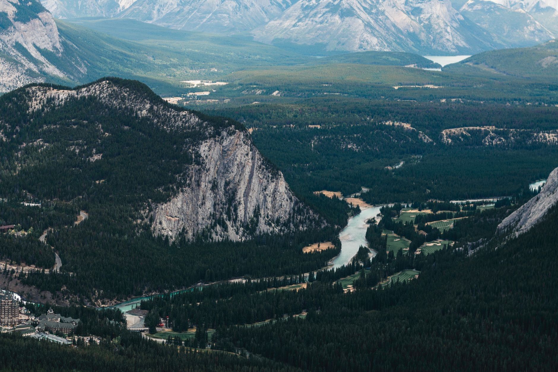 An elevated view overlooking the Bow River winding through forested mountains in Banff National Park.