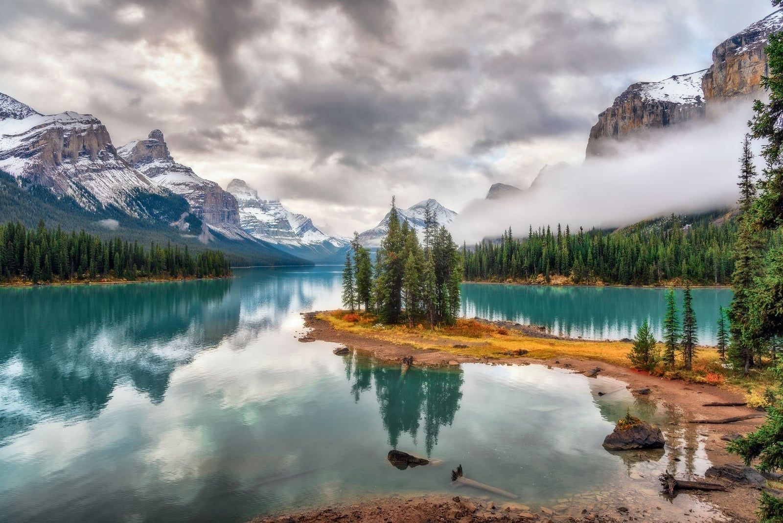Spirit Island entourée d'eaux turquoise et de montagnes poudrées de neige au lac Maligne dans le parc national de Jasper.