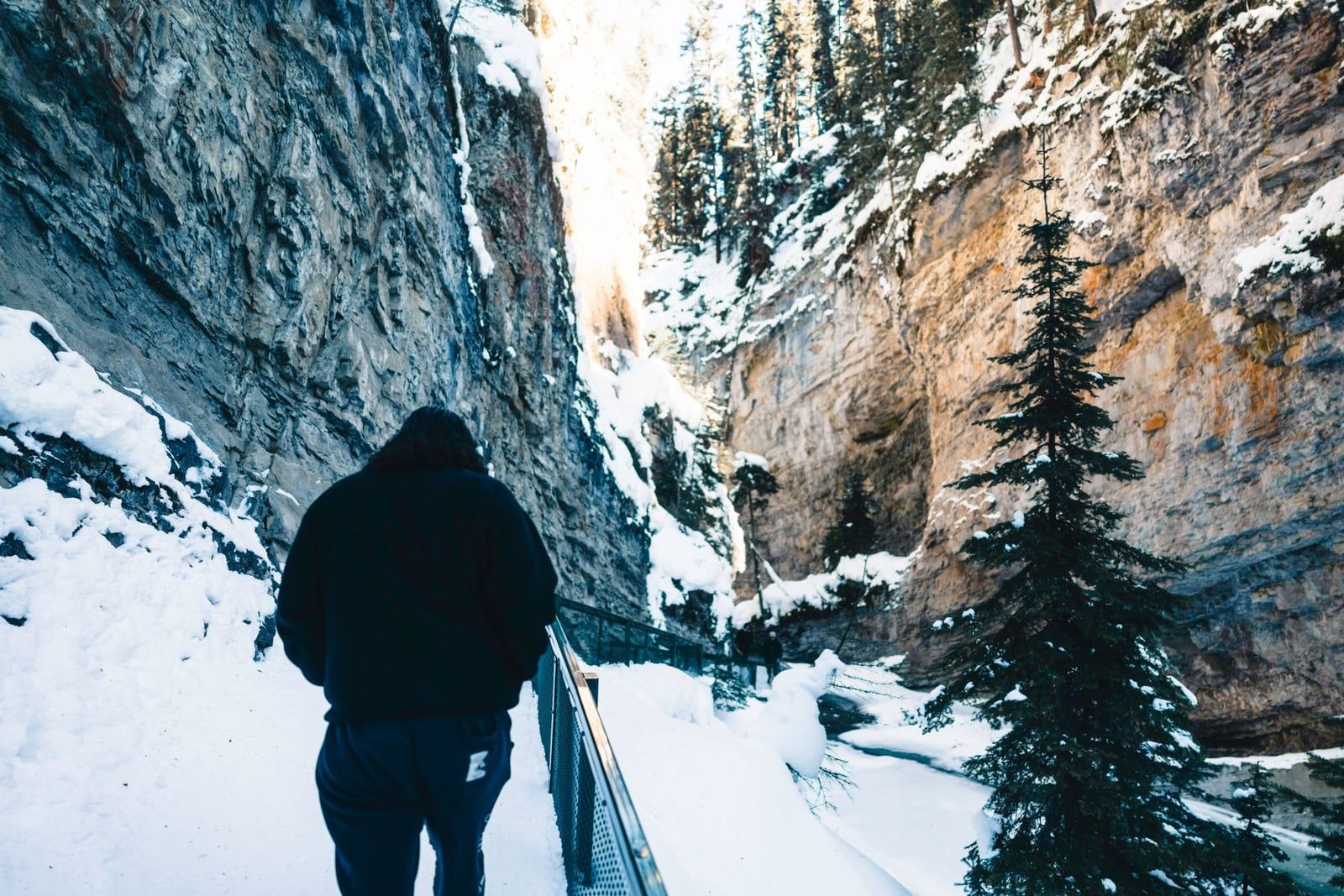 Un excursionista camina por una pasarela cubierta de nieve a través de un desfiladero escarpado en el Parque Nacional Banff.