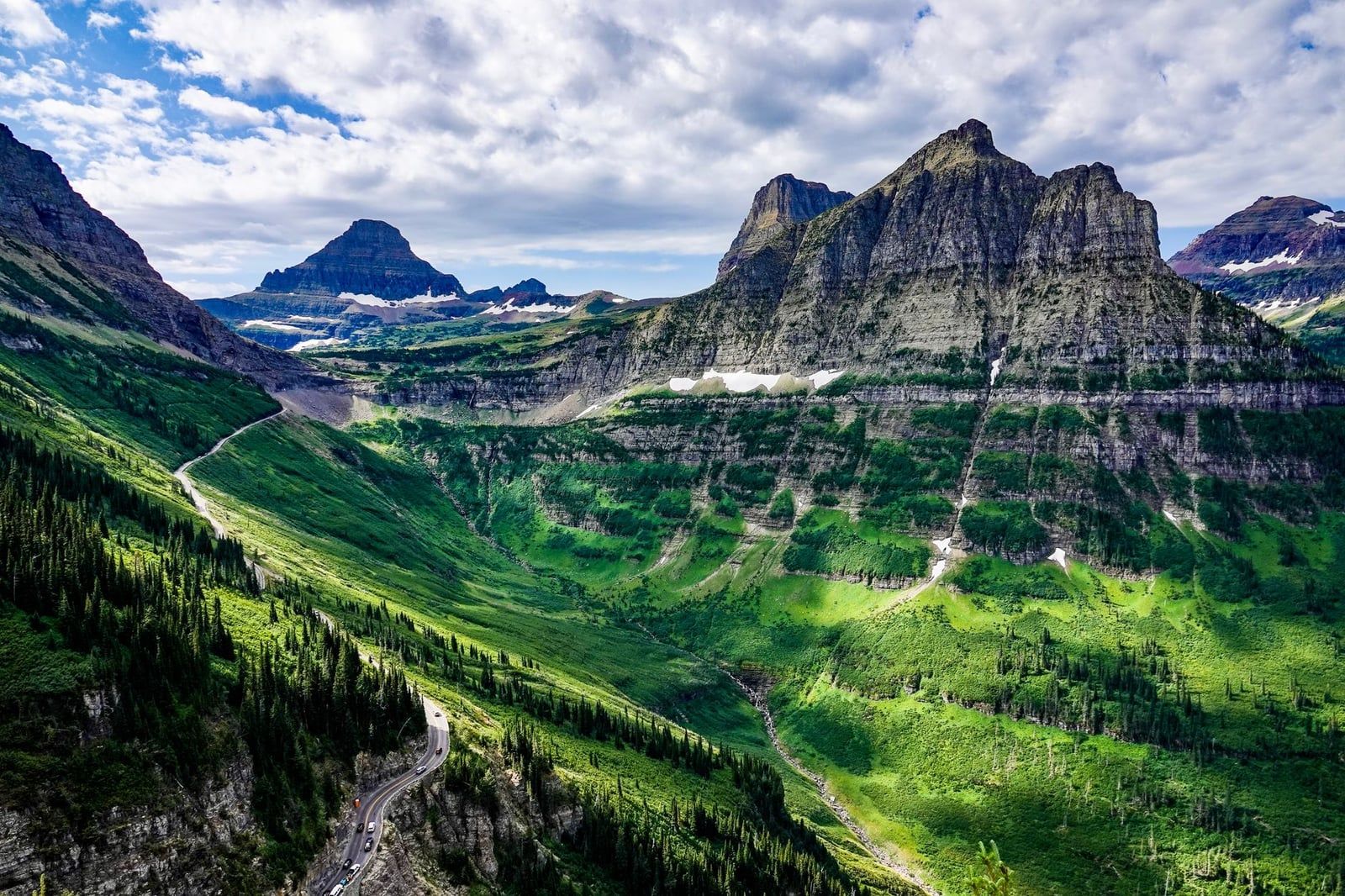 Going-to-the-Sun Road winds along lush green mountainsides and alpine valleys in Glacier National Park.