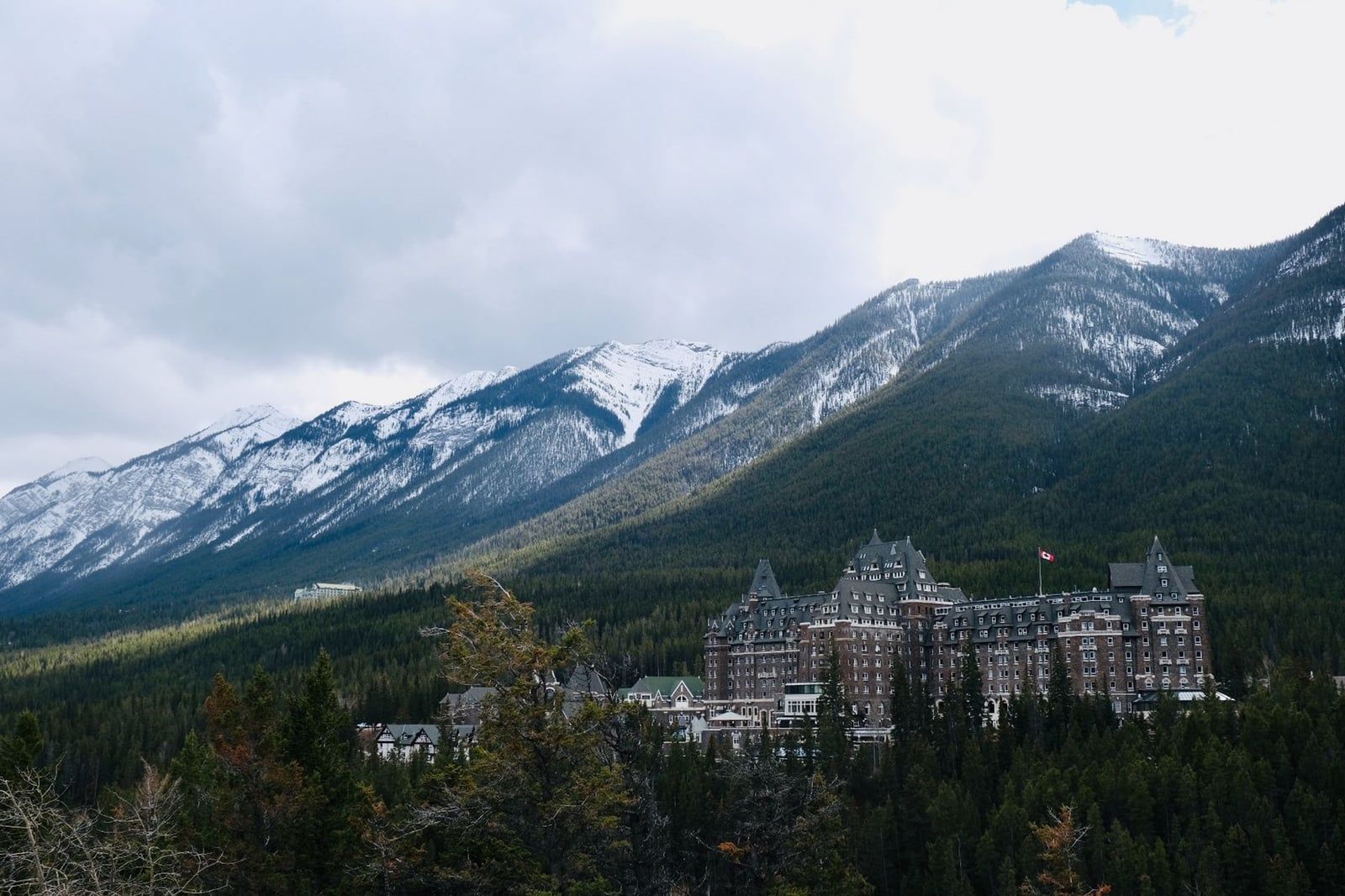 Das historische Fairmont Banff Springs Hotel schmiegt sich an dichte Tannenwälder unter hoch aufragenden, schneebedeckten Bergen im Banff-Nationalpark.