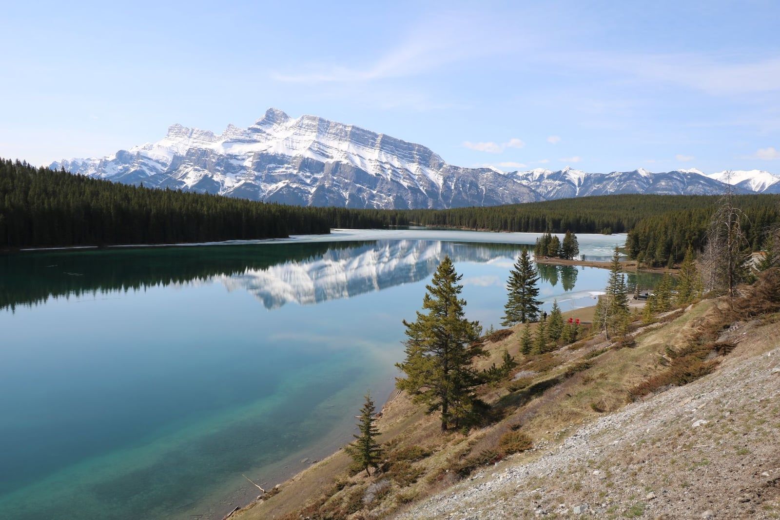 Der schneebedeckte Mount Rundle spiegelt sich im ruhigen türkisfarbenen Wasser und am Ufer des Two Jack Lake im Banff-Nationalpark.
